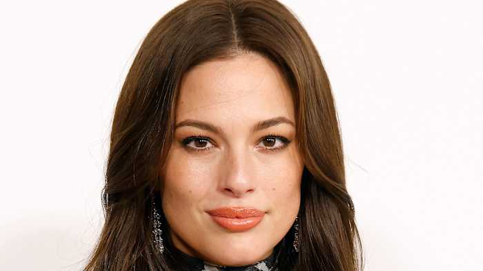 Ashley Graham poses with her brown hair in a down-do and sporting a glossy pink lip.